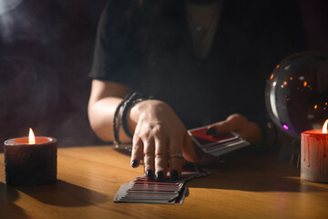 Soothsayer predicting future with cards at table indoors, closeup