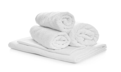 Rolled towels and folded bedding on white background