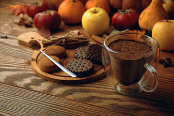 Mug of cocoa chocolate cookies and cinnamon sticks on wooden table. Autumn composition for postcards and invitations. Cocoa with chocolate chips. Concept of Christmas, Thanksgiving and Halloween.