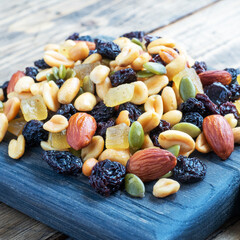 A mixture of nuts and dried fruits on a wooden chopping board, rustic background. Concept of healthy food.