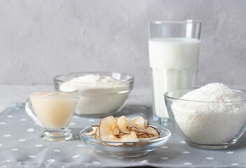 Coconut products: coconut flakes, flour, milk, condensed milk and chips on gray background. Healthy eating