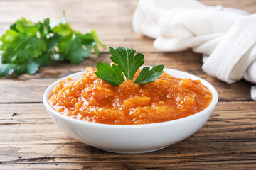 Homemade caviar from zucchini tomatoes and onions in a ceramic plate on a wooden background. Homemade production canning, canned stewed vegetable.