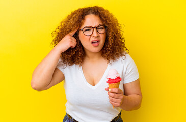 Young latin woman holding an ice cream isolated on yellow background showing a disappointment gesture with forefinger.