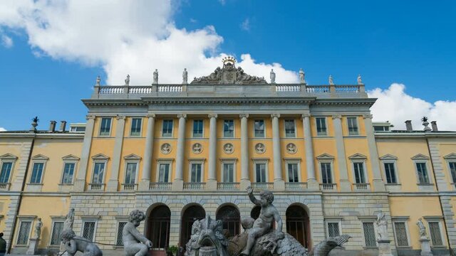 View of the facade of the famous Villa Olmo, Como, Italy, located close to the lake. On the foreground a beautiful fountain with statues. Blue sky and white clouds on the background. Time lapse.