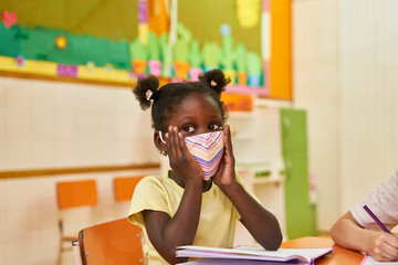 Afrikanisches Mädchen mit Schutzmaske im Kindergarten - obrazy, fototapety, plakaty