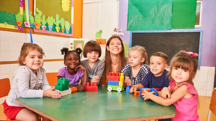 Glückliche Kindergärtnerin und multikulturelle Kinder - obrazy, fototapety, plakaty