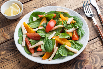 Salad of boiled squid, fresh tomatoes, spinach leaves. Delicious bright diet dish with vegetables and seafood.