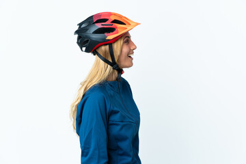 Young blonde Uruguayan cyclist woman isolated on background laughing in lateral position