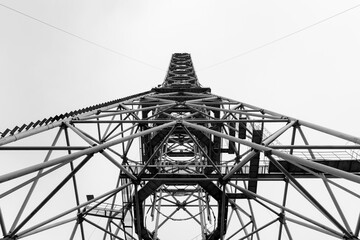 Construction of a large metal tower. Bottom view. Symmetry of metal structures. Monochrome image.
