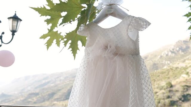 White baptism dress hanging on the branches of the vine. Close up shot with mountains in the background