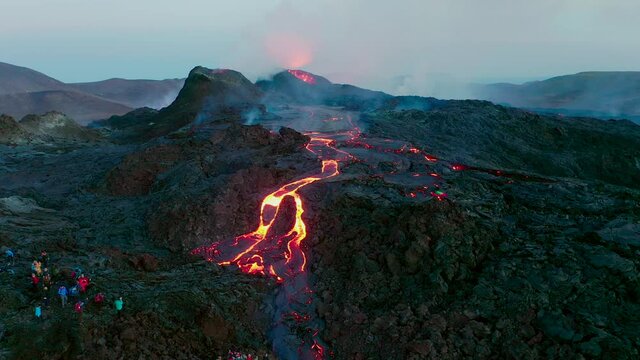 Aerial view of flowing hot lava after gigantic volcano eruption in Iceland. Many Tourists visiting place in the evening.