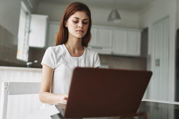 woman with laptop sitting at table freelancer working outside office kitchen interior