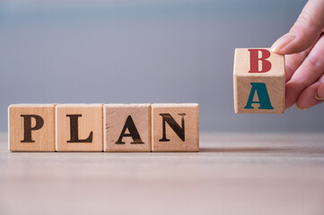 Hand flip wooden cube with the word PLAN A to PLAN B on wood background. Business concept © Reda