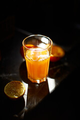 Illuminated orange juice glass with slices of lemon and oranges.