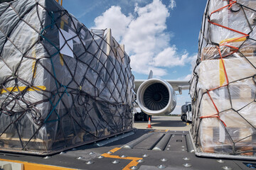 Preparation before flight. Loading of cargo containers against jet engine of freight airplane.  - obrazy, fototapety, plakaty