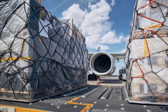 Preparation before flight. Loading of cargo containers against jet engine of freight airplane. 