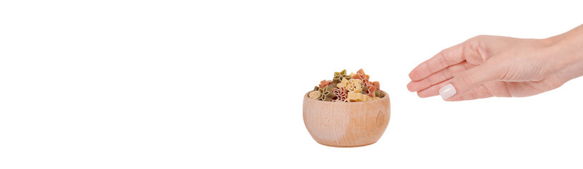 Hand with Colored fresh and raw pasta in wooden bowl. Isolated on white background.