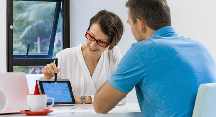 Realtor agent presenting a new project property on tablet pc for young customer.