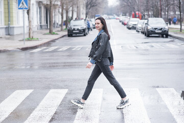 Beautiful brunette girl crosses the road on a pedestrian crossing