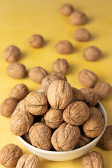 Pile of walnuts inside a bowl on a yellow background