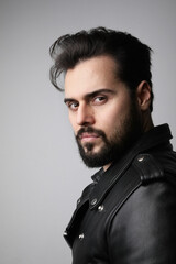 Vertical close-up portrait of young handsome bearded man, posing in the studio.
