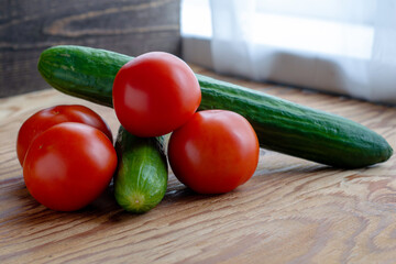 two cucumbers and four tomatoes on a wooden background