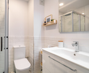 Modern bathroom with white ceramic tiles and shower cabin reflected in mirror