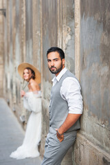 Stylish handsome bearded arab groom in a gray suit. Young couple posing on the street of the old city.