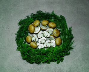 Fototapeta na wymiar champignons and greens beautifully laid in the form of a wreath on a gray background