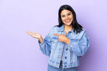 Young latin woman woman over isolated background holding copyspace imaginary on the palm to insert an ad