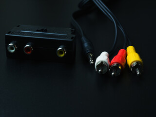 Audio-video adapter with plugs on dark background.