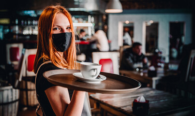 Portrait young waitress standing in cafe. girl the waiter holds in bunches a tray with utensils. Restaurant service