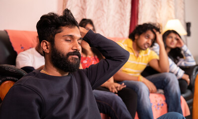 Close up of focus on young disappointed man, Group of young sports fans sad over loss of game while watching live streaming sports match on television at home.