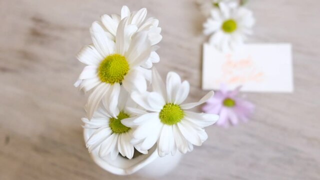 Summer flowers chamomiles.  Summer bouquet in white vase and card with message Just Smile