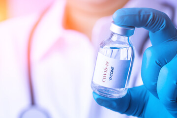 Obraz premium Doctor with a stethoscope on shoulder holding syringe and COVID-19 vaccine. Healthcare And Medical concept. Discovery Healing and End of Pandemic Living with COVID 19 Vaccine . Coronavirus Vaccine.