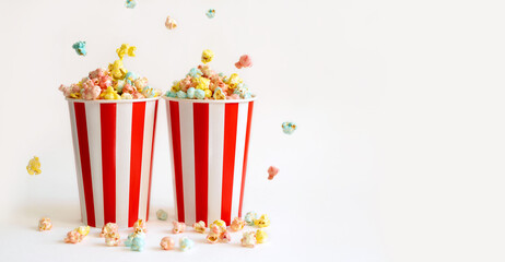 Two large filled glasses with colorful sweet popcorn for fun watching movies in the cinema. banner....