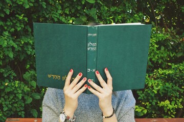 Girl with red nails reads the  hebrew book  - obrazy, fototapety, plakaty