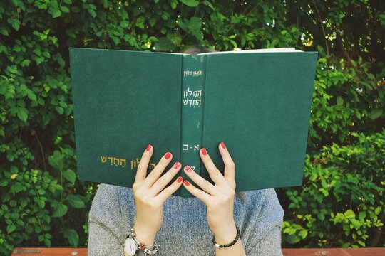 Girl with red nails reads the  hebrew book 