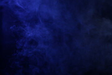 Smoke illuminated in purple on a black background in darkness