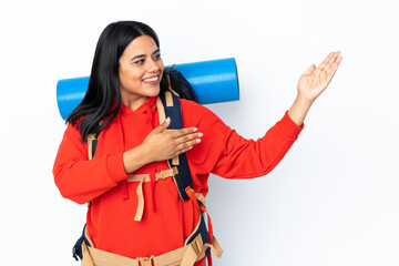 Naklejka premium Young Colombian mountaineer girl with a big backpack isolated on white background extending hands to the side for inviting to come