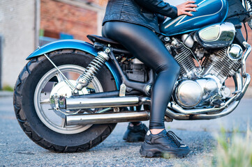 Obraz na płótnie Canvas A woman in leather leggings is sitting on a motorcycle. close uo of female legs on a bike