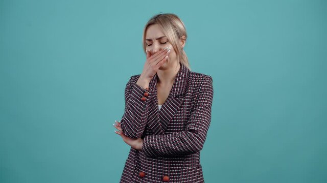 The portrait of a young woman disgusted by the bad smell, frowns and puts her hand to her nose to cover it.Isolated on a turquoise background. The concept of life. People's emotions. Portrait 4k