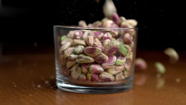 Pistachios nuts falling in the glass jar