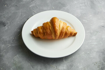 Delicious French pastries - air croissant, on a white plate on a black background