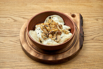 Traditional Ukrainian dumplings filled with mashed potato topping with fried mushroom and sour...