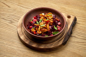 Traditional Ukrainian salad of beets, potatoes, onions, pickled cucumbers, served in a bowl on a wooden background. Diet Vinegret with honey fungus