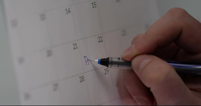 Man's hand wright a sign on calendar. Close-up Macro Shot. Signature Is Fake
