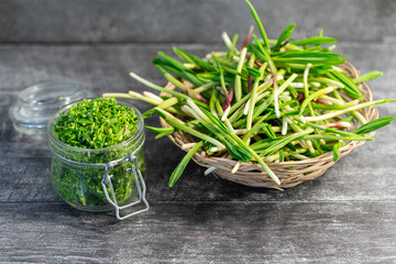 Wild leek pesto with olive oil in a glass jar on a wooden table. Useful properties of wild garlic. Fresh bear onion leaves.