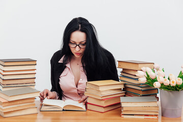 beautiful business woman in business suit at a table with stacks of educational books
