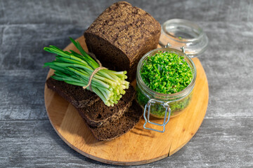 Wild leek pesto with olive oil in a glass jar on a wooden table with bread. Useful properties of wild garlic. Fresh bear onion leaves.